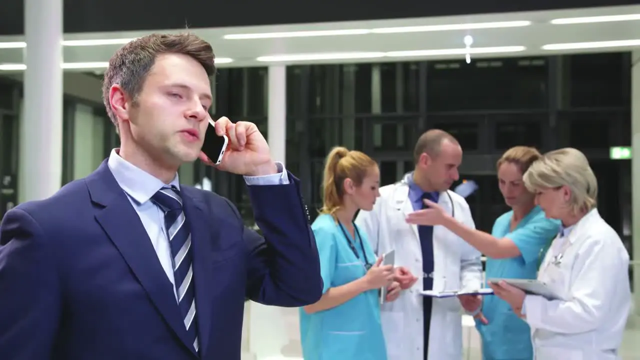 Businessman talking on mobile phone in hospital corridor