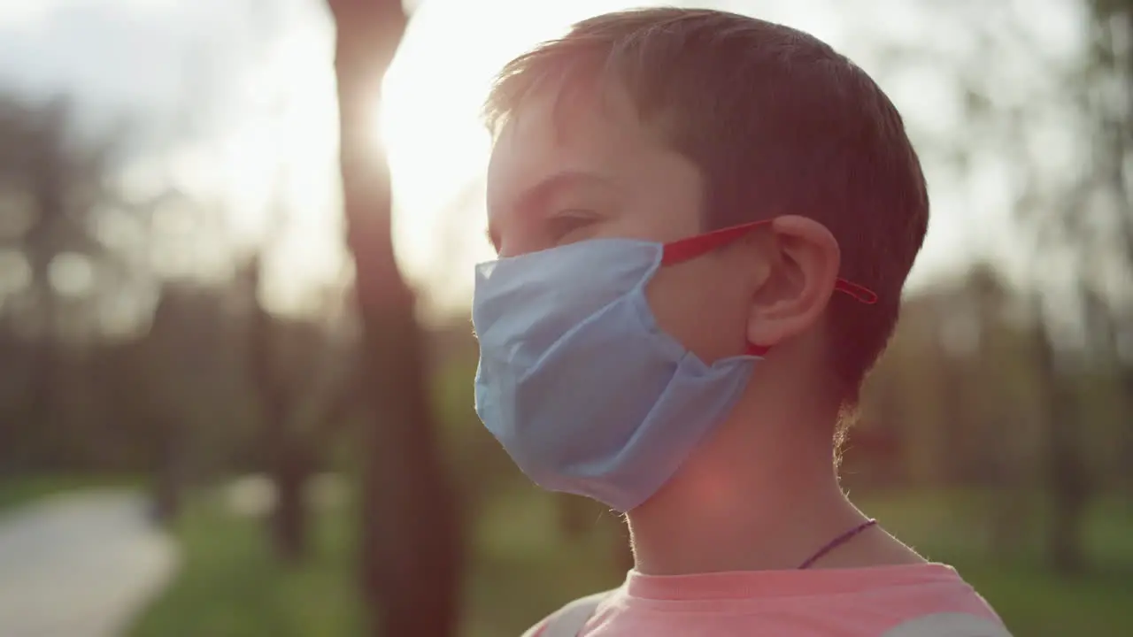 Young guy standing in medical mask outdoors Teen boy caring from coronavirus