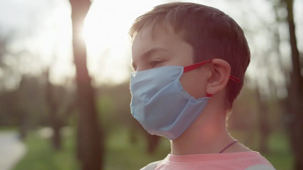 Serious guy standing in medical mask at outdoors Teenager boy taking away mask