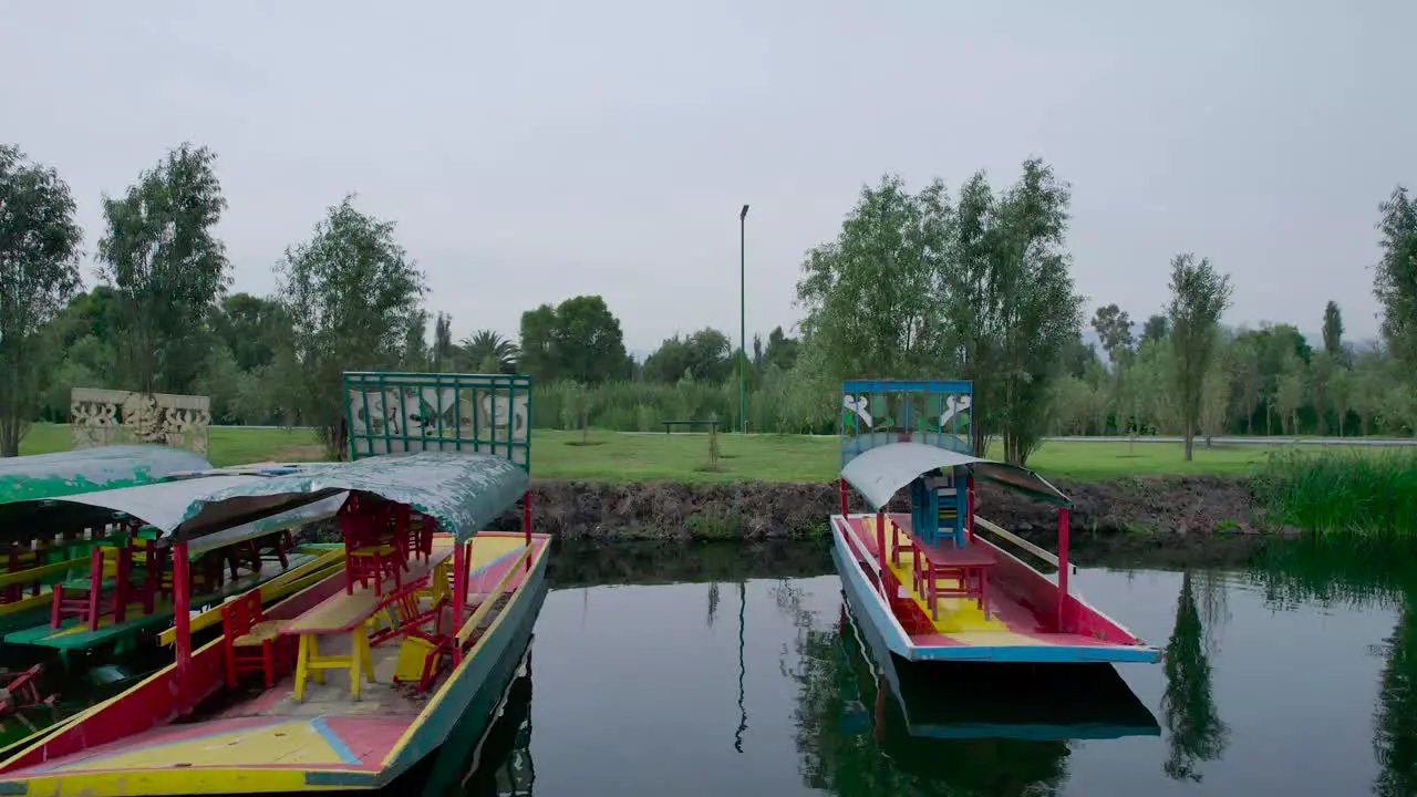 Dolly out in middle of trajineras above a lake and natural area with view of a trail in Xochimilco Mexico City