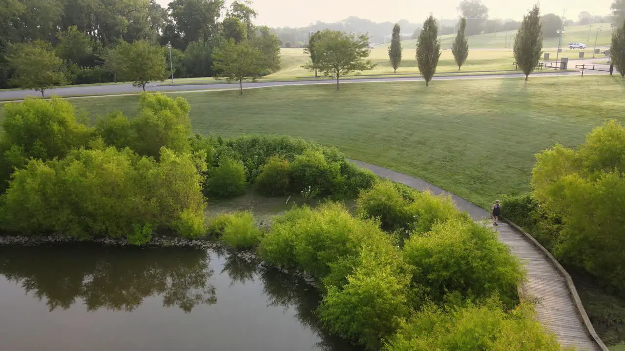 Aerial footage of female jogger at a green park during sunrise