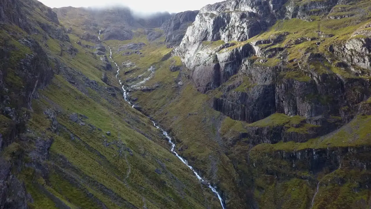 Steep whitewater creek runs down steep craggy mountain highland valley