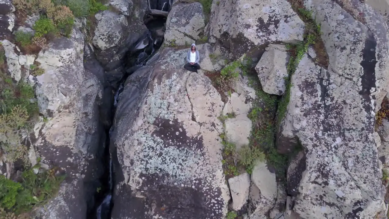 A man meditating on the rocky cliff of a mountain in Madeira Portugal Aerial shot