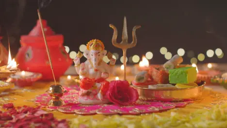 Person Holding Incense Stick By Statue Of Ganesh On Decorated Table Celebrating Festival Of Diwali