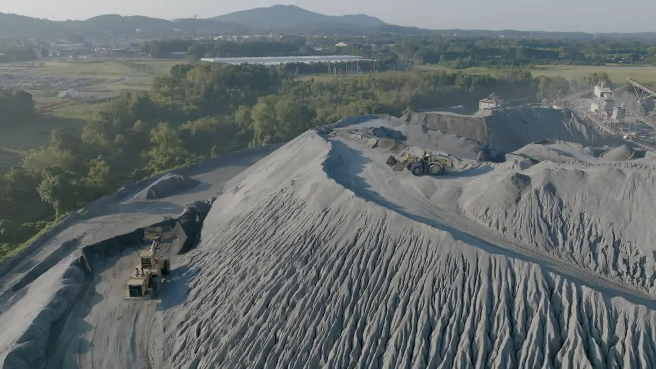 Bulldozers moving material on top of a large hill of gravel