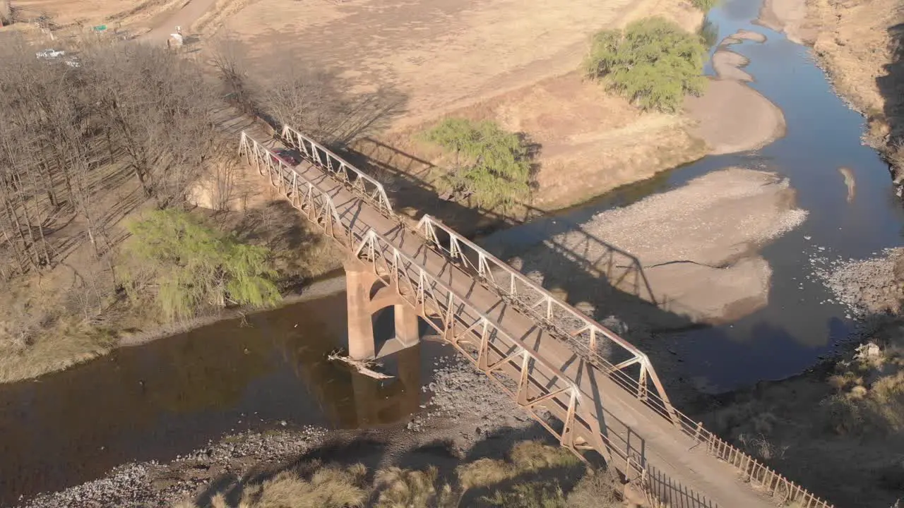 aerial locked off shot of a car crossing an old steel bridge