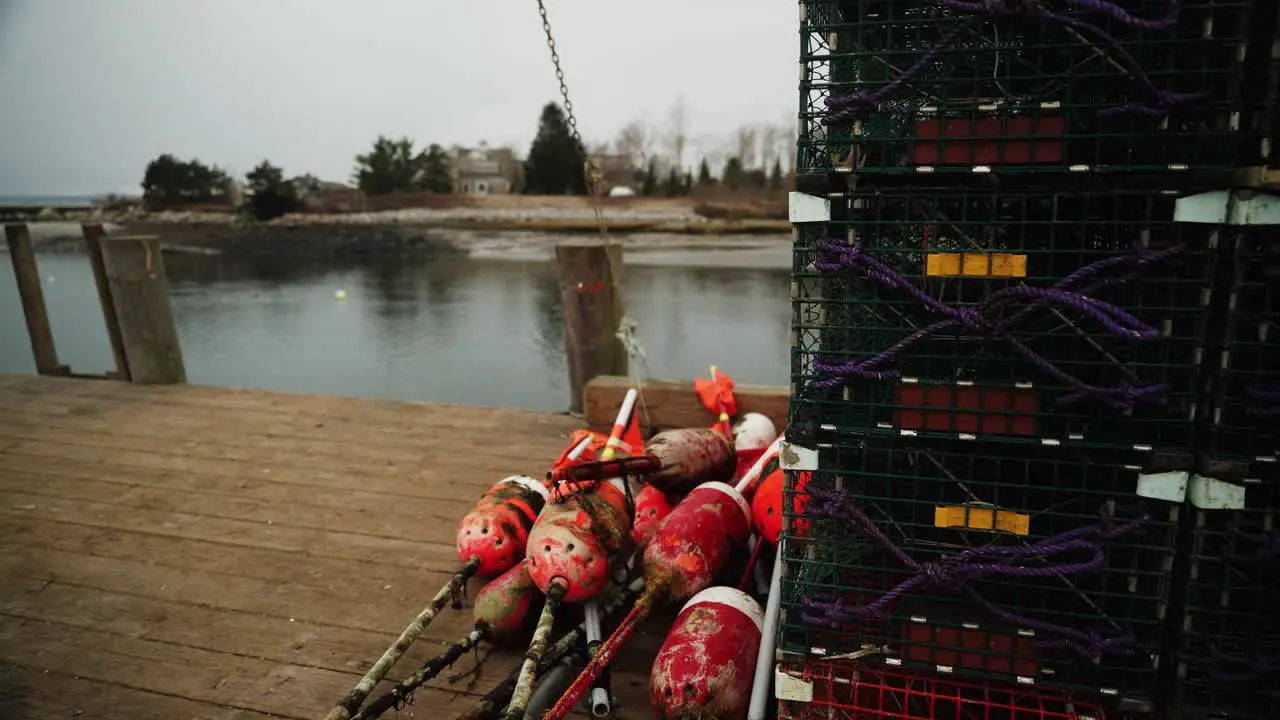 Lobster traps and fishing buoys on pier in Maine tilting wide shot