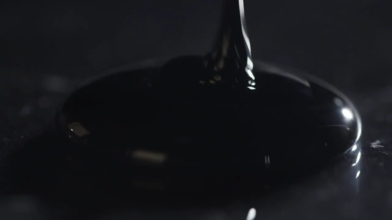 Oil Being Poured onto Black Surface