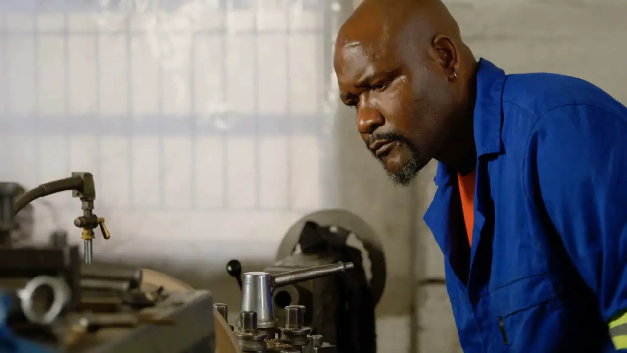 Metalsmith looking at machine in workshop 4k