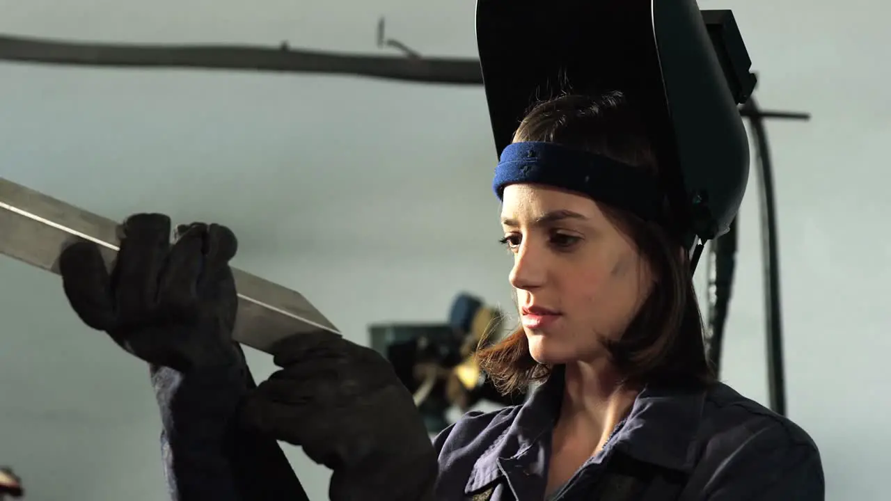 Female welder examining a piece of metal