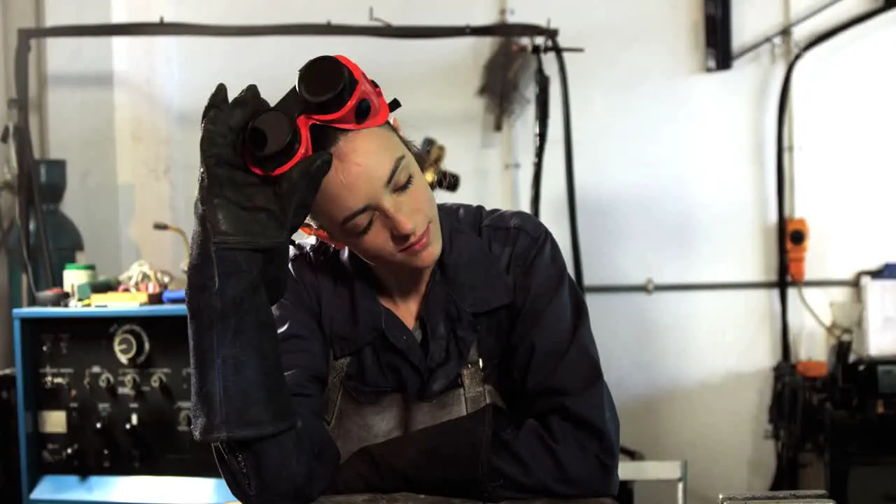 Female welder leaning in workshop