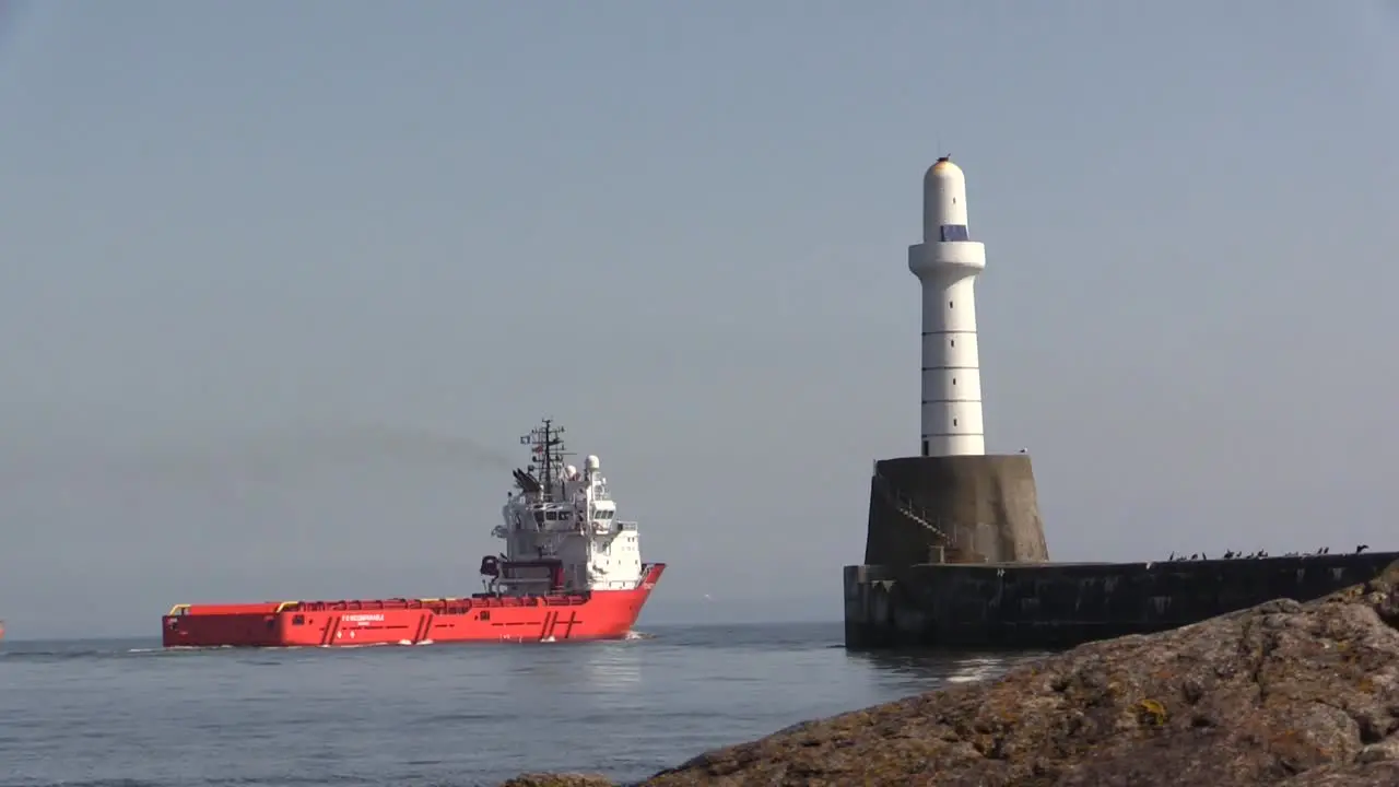 Aberdeen Harbour with ship leaving past lighthouse on a sunny day