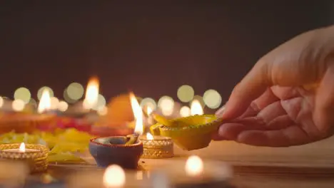 Person Lighting Diya Lamp Onto Table Decorated To Celebrate Festival Of Diwali