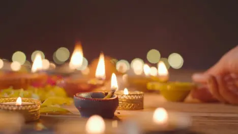 Person Lighting Diya Lamp Onto Table Decorated To Celebrate Festival Of Diwali 1