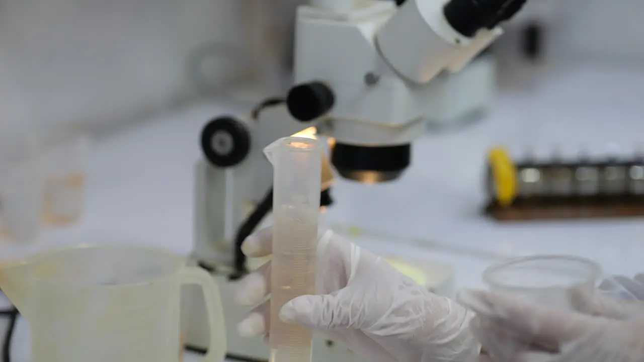 Scientist pouring water sample from test tube to water cup lab analysis