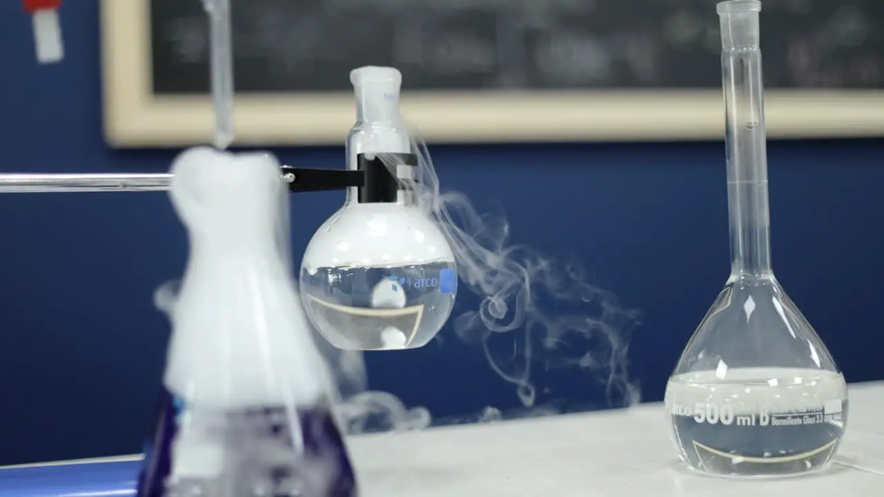 In a methodical slow-motion capture glass beakers in a laboratory bubble vigorously releasing white smoke demonstrating the intricate processes and marvels of chemical research