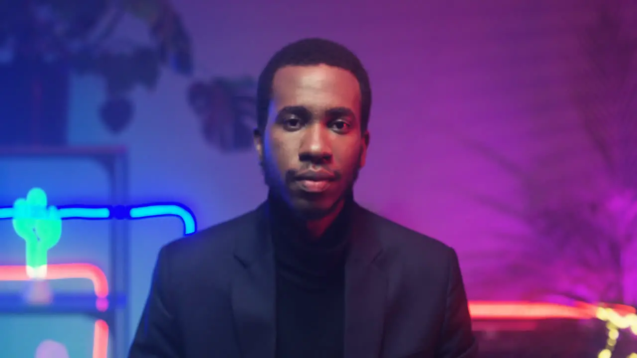 Close Up Of Young Attractive Man Looking To Camera In Room With Neon Pink And Blue Lights