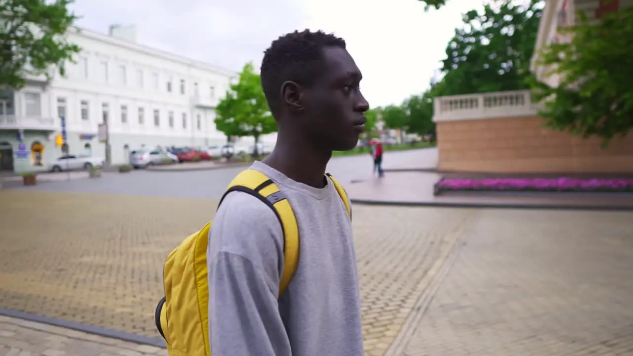 Handsome Young Man Walking In City With Yellow Backpack On Shoulders Wearing Casual Clothes