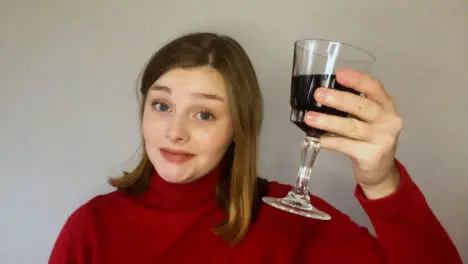 Female Young Student Talking and Raising Glass Directly to Camera