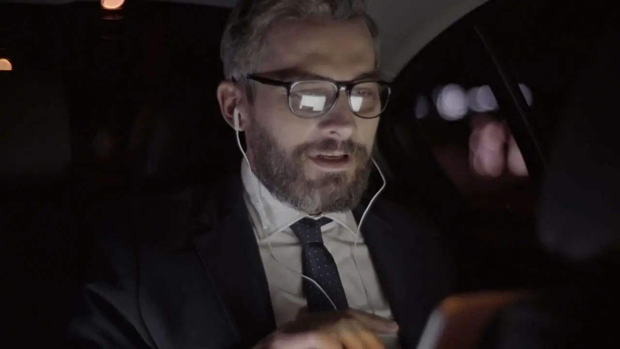 Businessman With Gray Hair Glasses And Stylish Clothes Greets On A Video Call While Traveling By Car