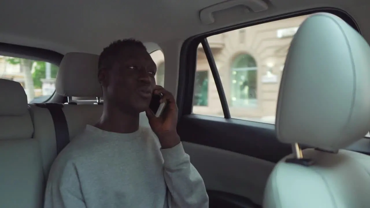 Positive Smiling Man In Casual Clothes Talking On Cellphone While Riding In Backseat Of Taxi Cab