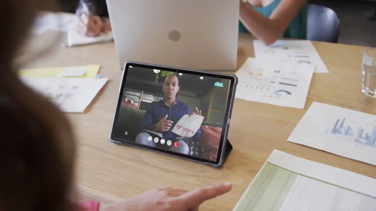 Caucasian businesswoman on tablet video call with african american male colleague on screen