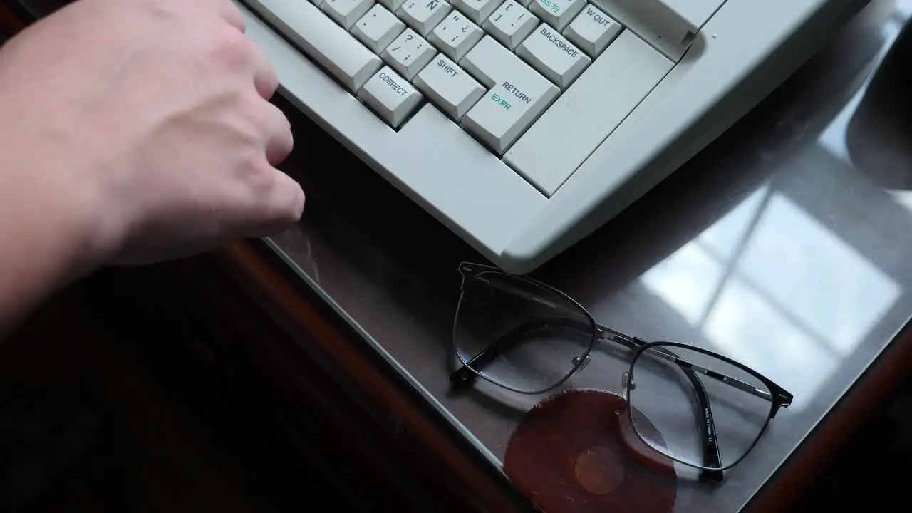 Person Typing on a Typewriter With Their Glasses on the Desk in Slow Motion