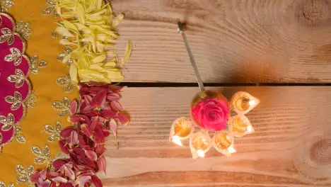 Person Holding Five Wick Lamp On Table Decorated To Celebrate Festival Of Diwali