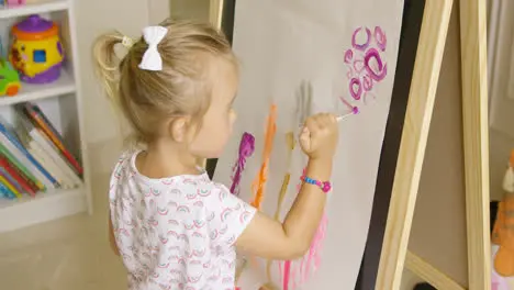 Creative little girl painting in a playroom