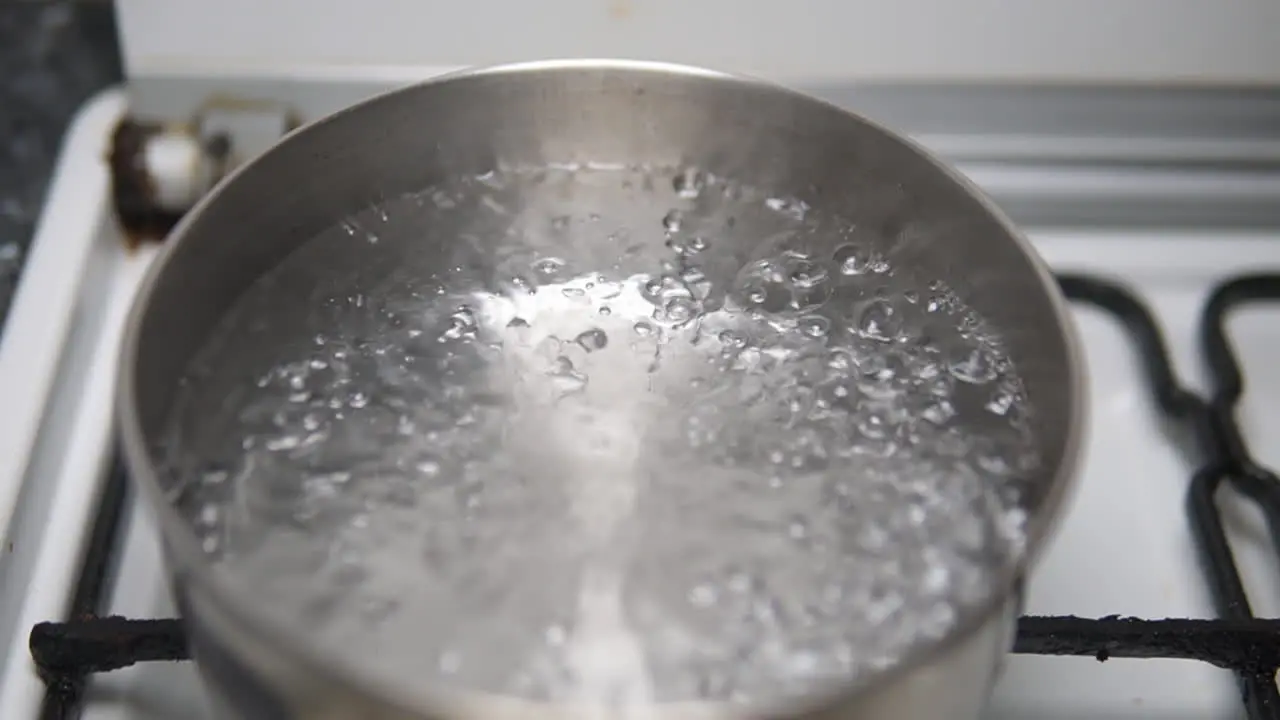 Push in to water boiling in a rusty old stainless steel pot on the fire stove