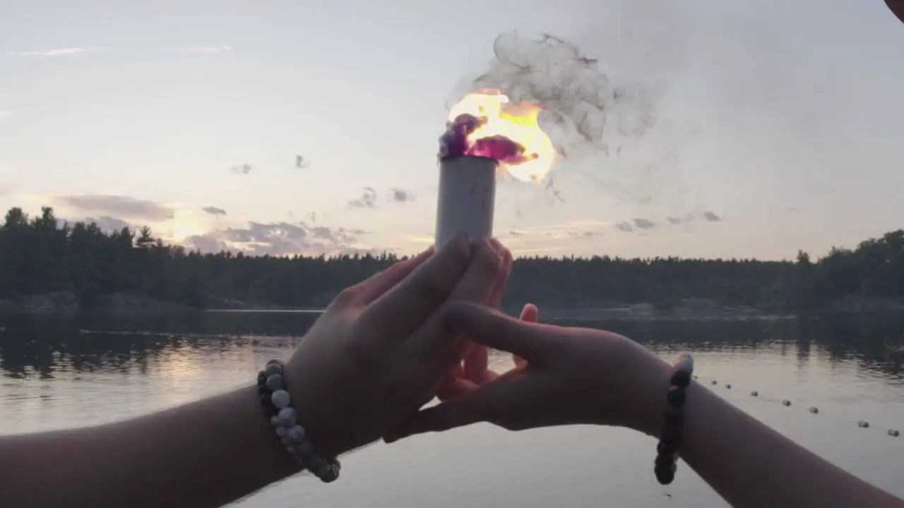 Two person hold a colored smoke bomb in hands while walking into a lake slow motion