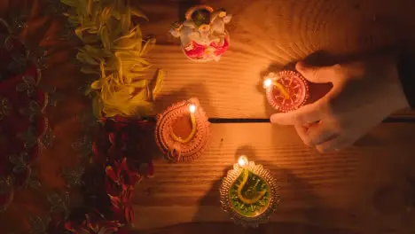 Hand Putting Diya Lamp On Table Decorated For Festival Of Diwali With Statue Of Ganesh 1