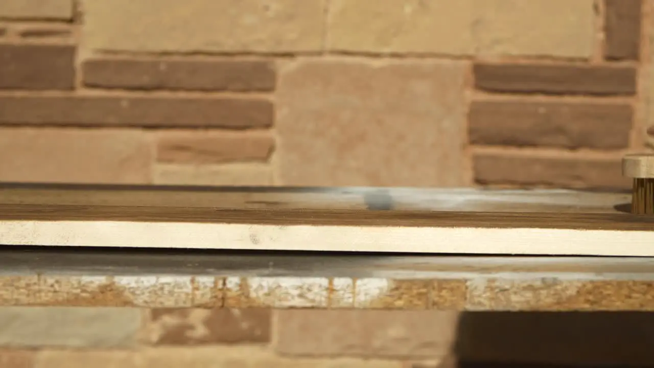 Carpenter applying wire brush on burned pine wood plank then touching and feeling surface close up