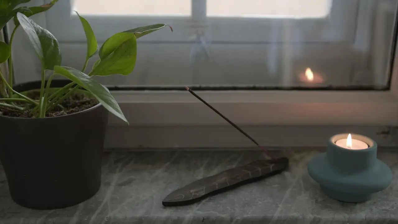 Smoke form incense stick and relaxing candle next to living room window yoga and meditation ritual