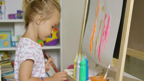 Cute little blond girl painting with watercolors