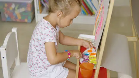 Adorable little girl mixing colorful paints