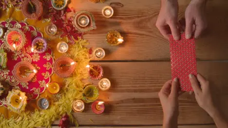 Overhead Shot Of Person Receiving Gift Of Money With Burning Lamps Celebrating Festival Of Diwali