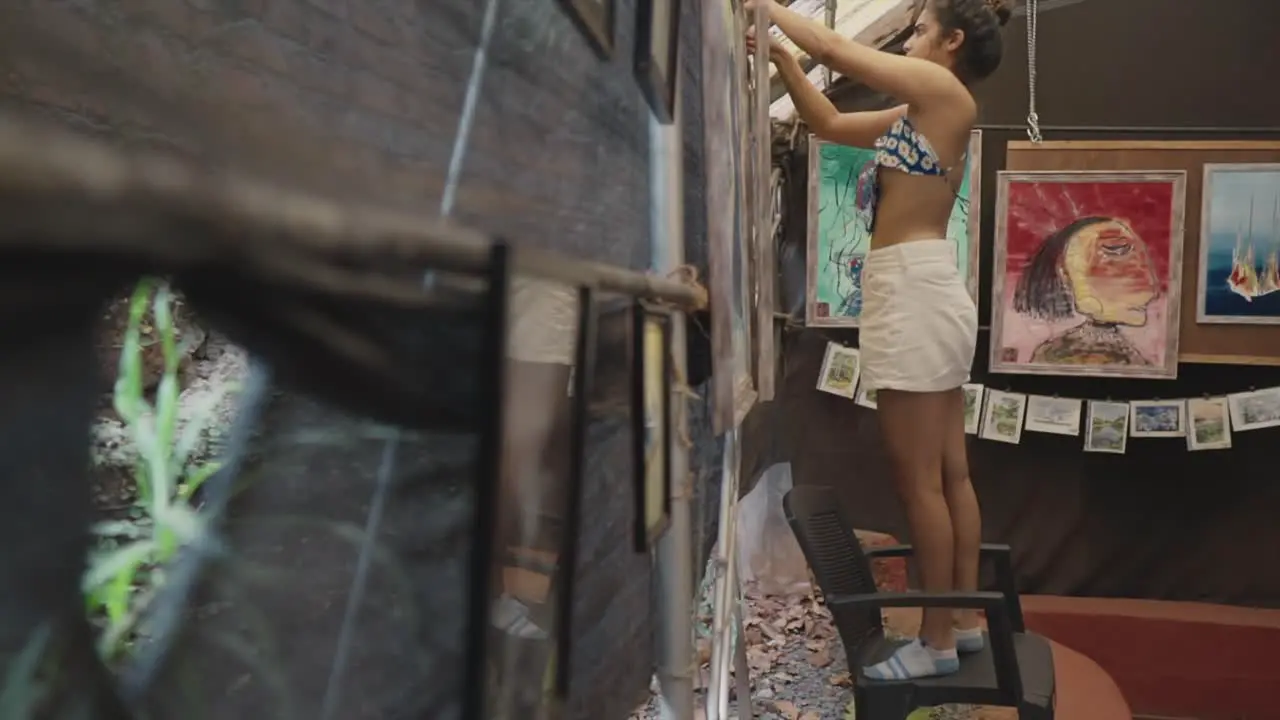 Slow-motion shot of an Indian woman meticulously hangs her artwork at an art gallery