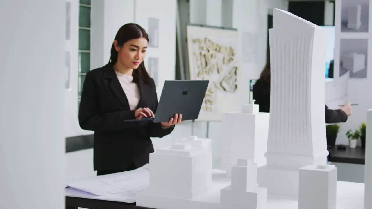 Real estate agency worker measuring printed building maquette