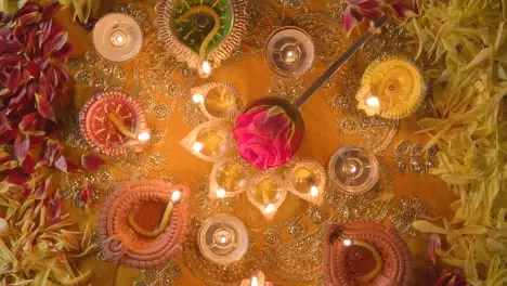 Overhead Turntable Shot Of Five Wick Lamp On Table Decorated For Festival Of Diwali