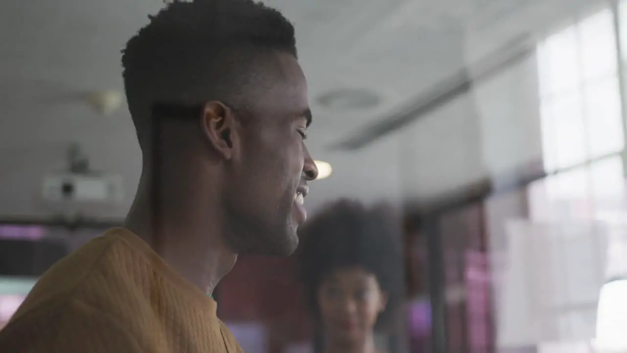 Happy african american male and female business colleagues brainstorming in meeting room