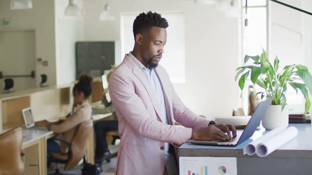 African american businessman using laptop with colleagues in creative office