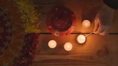 Clay Pot With Tea Lights Being Lit To Celebrate Indian Wedding Diwali Or Navratri On Decorated Table