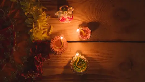 Lit Diya Lamps On Table Decorated For Festival Of Diwali With Statue Of Ganesh