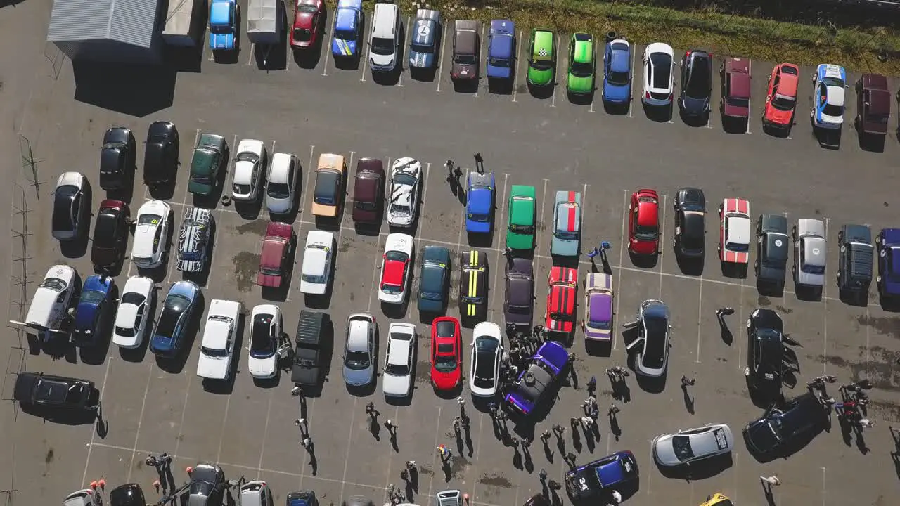 Drifting race cars parking lot with dozens of cars aerial top down shot