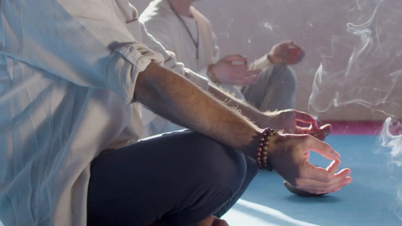 Men meditating with smoke from incense sticks around them