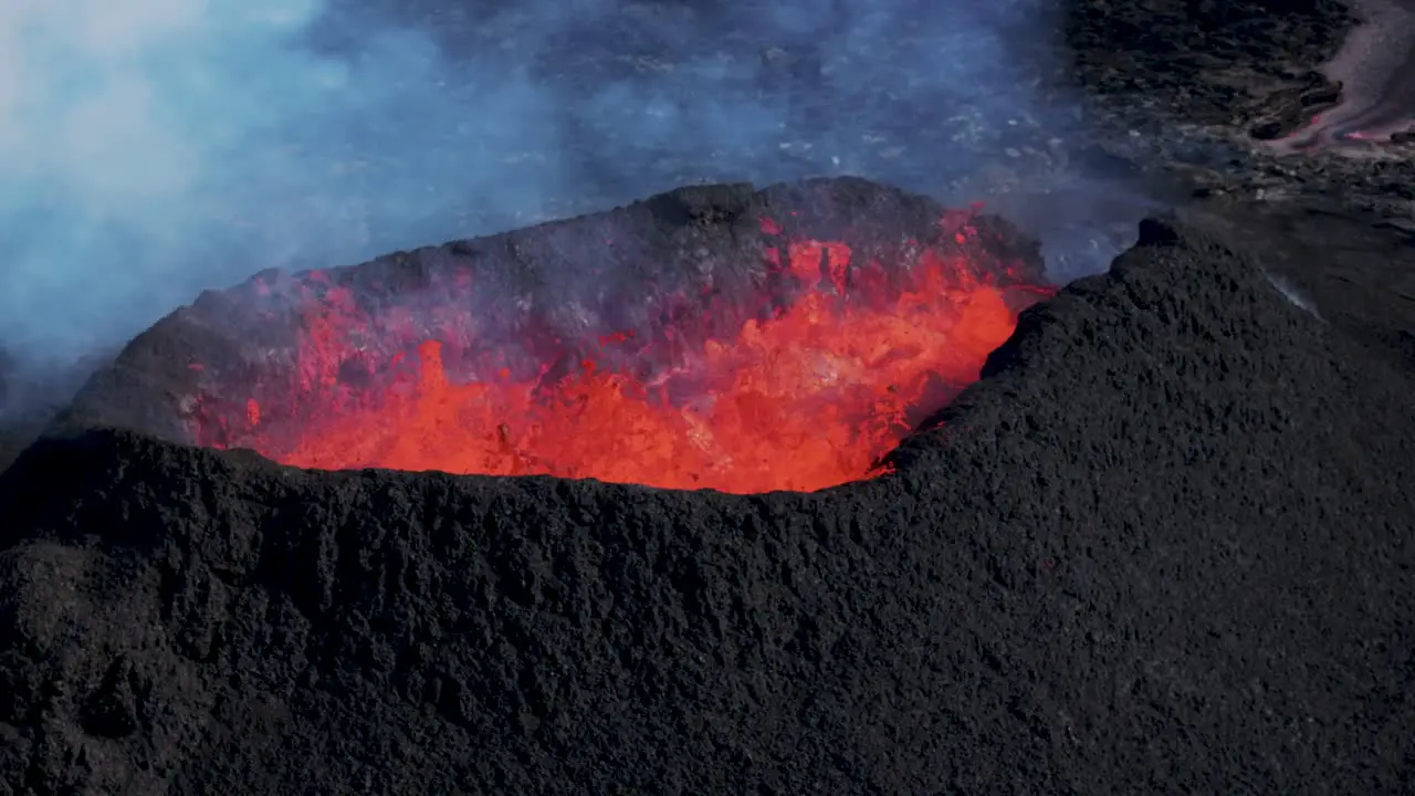 Basalt rock volcano mound with molten magma ejecting from crater Iceland