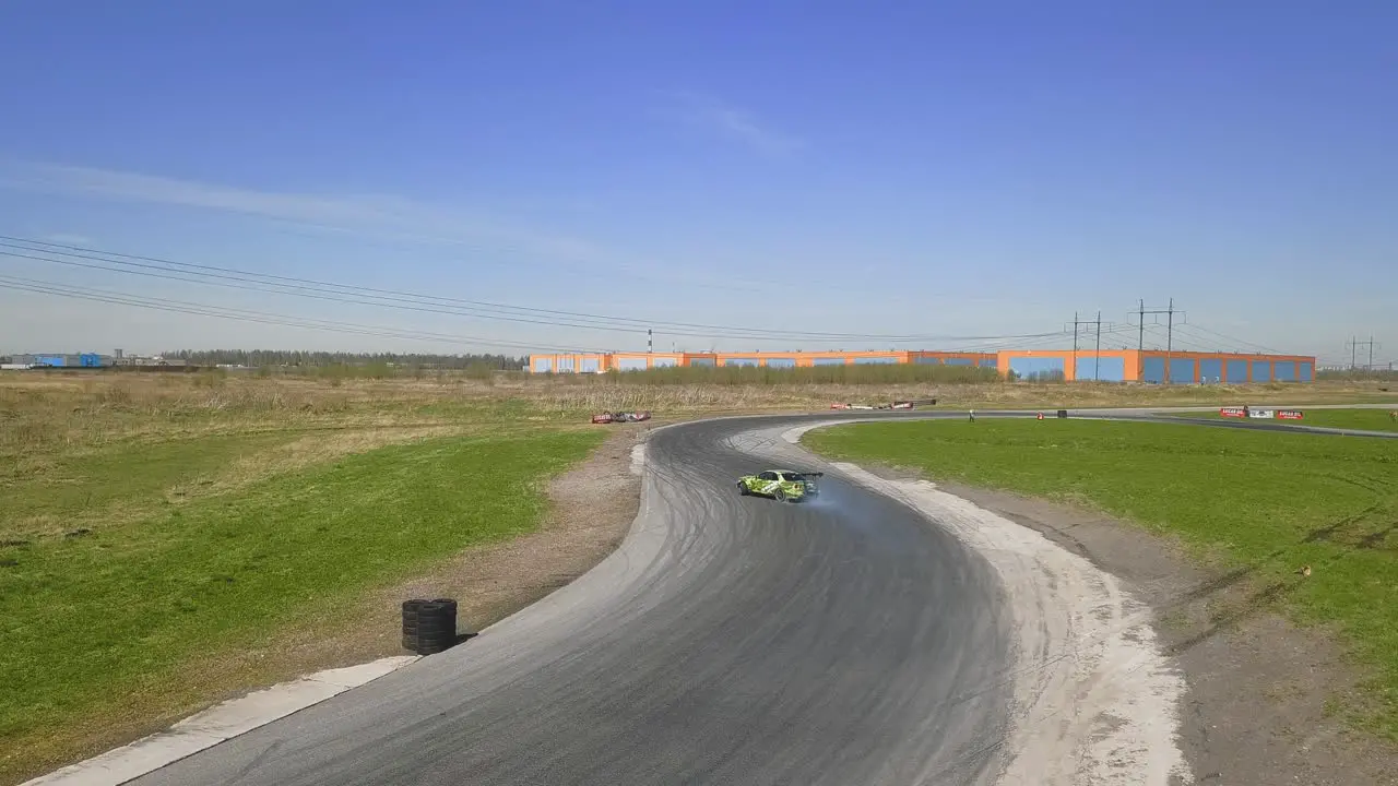 Green racing car drifting on a track with smoking tires and skid marks on an asphalt