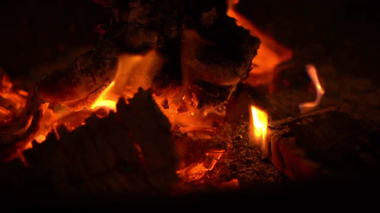 Night shot of red hot bonfire flames burning from glowing red coals with a few small sparks flying out of the fire