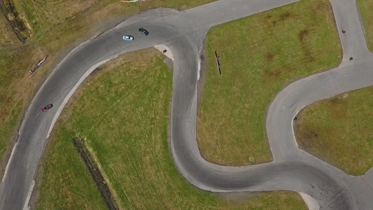 Top down aerial still view on a race track with drifting cars smoking tires and sunny weather